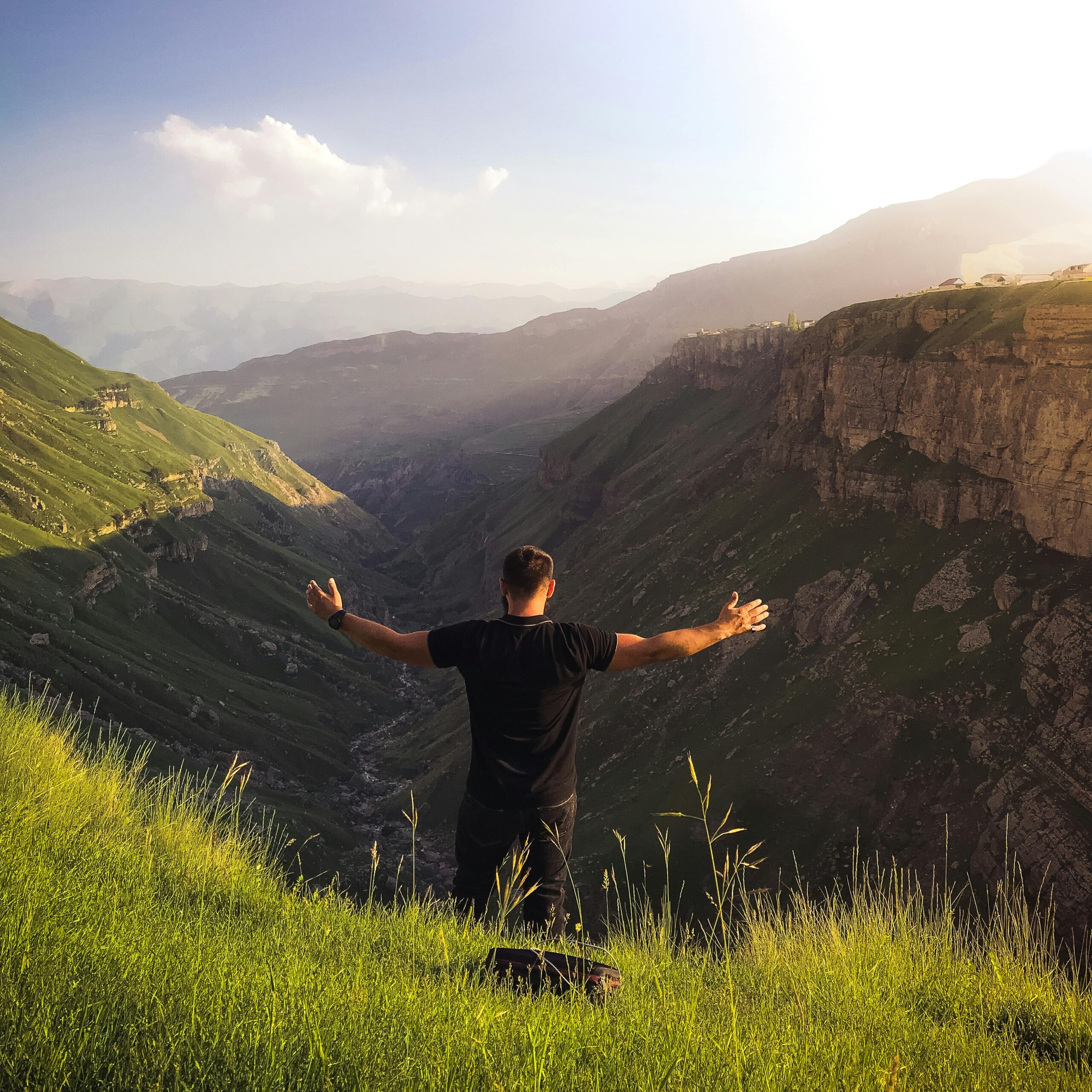 A man with open arms enjoys the breathtaking mountain view at sunrise, capturing the essence of freedom and adventure.