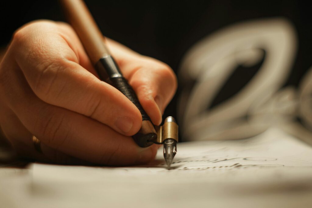 Artistic close-up of a hand using an oblique pen for calligraphy.