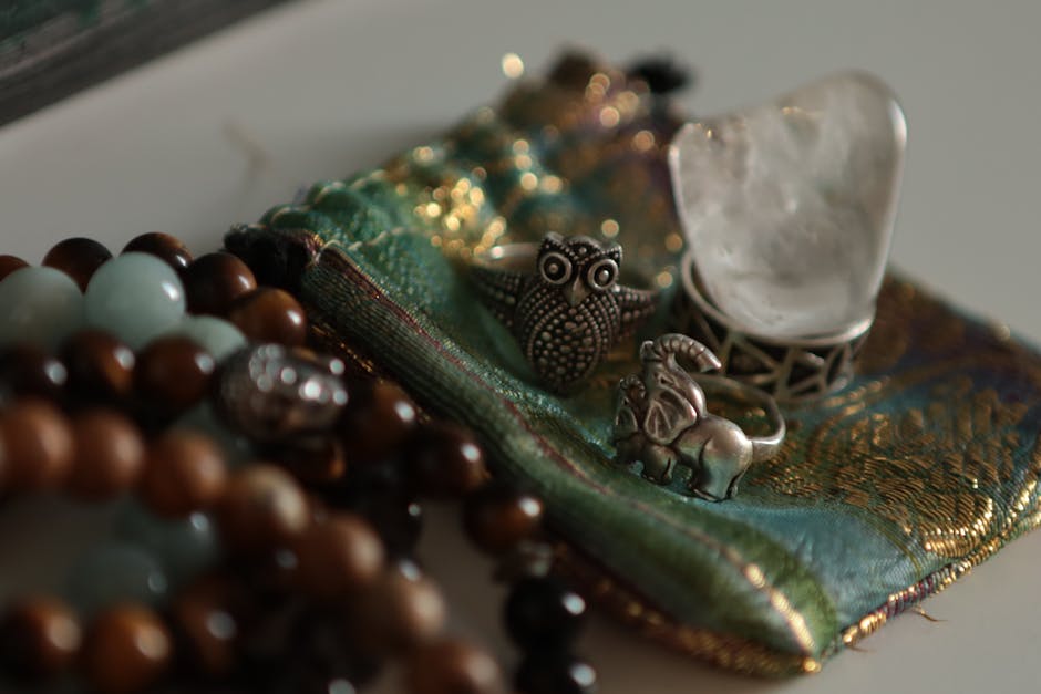 Close-up of beaded and metal jewelry arranged on decorative silk fabric, highlighting intricate craftsmanship.