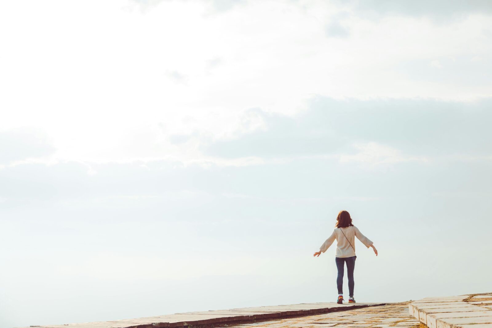 A woman standing on a hilltop embracing the open sky with a sense of freedom.