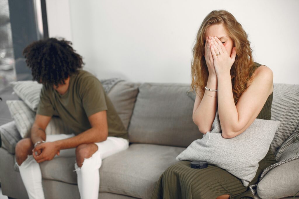 Couple experiencing emotional conflict on a sofa indoors with depth of field effect.