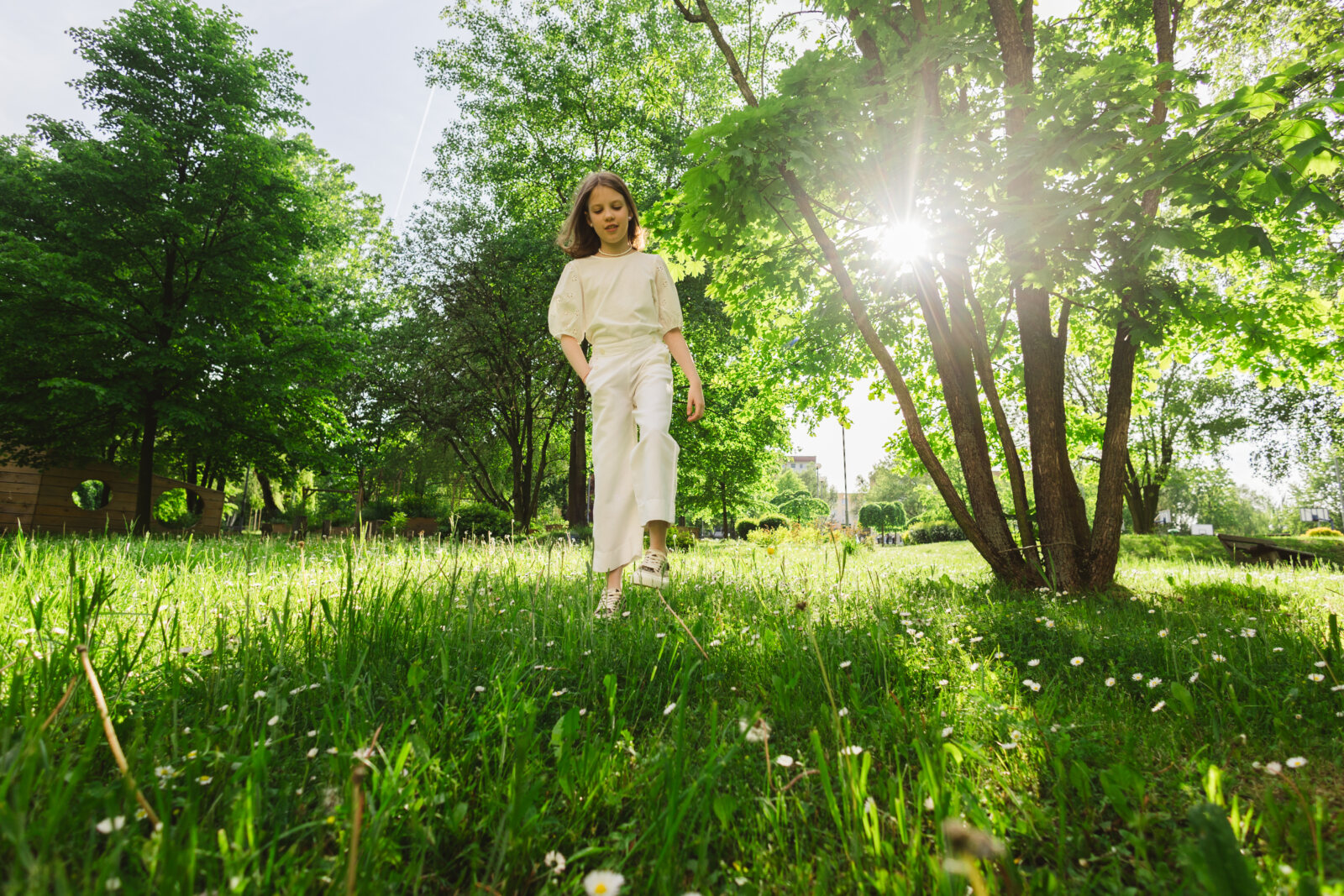 Žena u laganoj šetnji kroz sunčani park, vežba šetnja radosti za podizanje vibracija